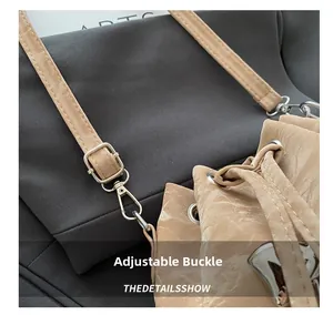 Detail of beige pleated bag featuring silver metal buckle and adjustable shoulder strap