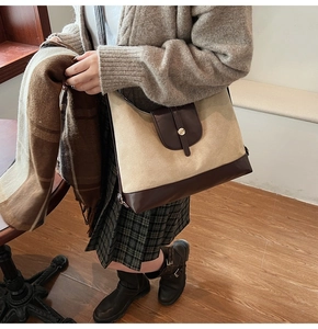 Detail of the large canvas and leather tote bag showing color-block design and golden buckle