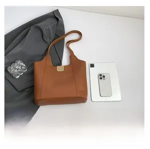 Detaillierter Größenvergleich der braunen Ledershopper mit Tablet und Mobiltelefon