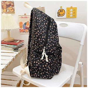 Detail of black floral canvas backpack featuring tulip patterns and woven zipper knot