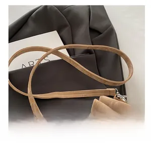 Close-up of beige leather shoulder strap with silver buckle on a pleated bucket bag