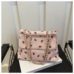 Detailed shot of pink corduroy shoulder bag featuring strawberry print and gold chain strap