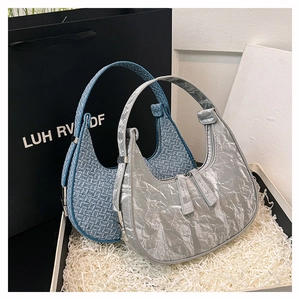 Close-up of blue woven and silver metallic crescent hobo bags in a gift box