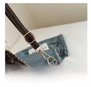 Détail de crochets en métal doré et bandoulière réglable sur sac en cuir marron foncé