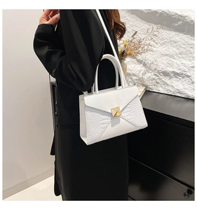 Detail of white crocodile embossed leather handbag with elegant gold square twist lock