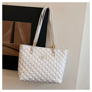 Close-up of diamond quilted white tote bag featuring gold hardware and logo detail