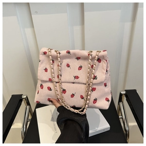 Detailed close-up of pink corduroy shoulder bag with strawberry print and gold metal chain
