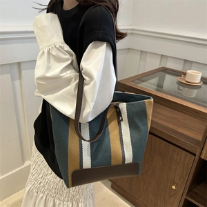 Detail of striped canvas tote bag with dark brown leather straps and vintage texture