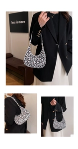 Close-up of leopard print baguette bag featuring golden buckles and a white strap