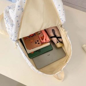 White canvas backpack with blue star prints showing large capacity for books and iPad
