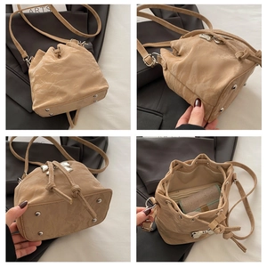 Detail of khaki pleated bucket bag with drawstring closure and silver bottom studs