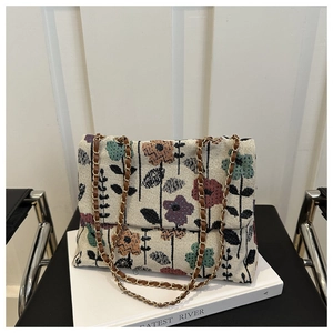 Macro detail of retro floral tapestry bag featuring thick textured weave and gold chain