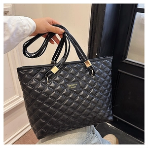 Close-up of black quilted tote bag with diamond pattern and gold metal hardware detail