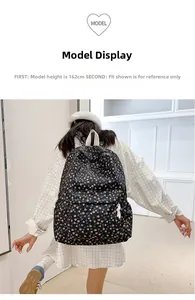Floral print black canvas backpack shown on a model with white woven straps for size reference