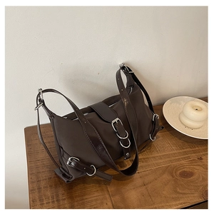 Détail du sac en cuir mat marron foncé avec boucles métalliques vintage sur bois