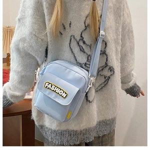 Detail of light blue nylon crossbody bag with fashion embroidery on the front pocket