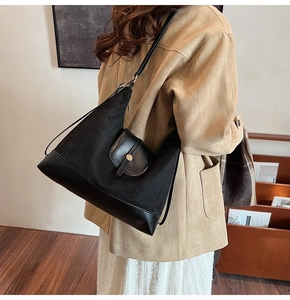 Detail view of black tote bag showing premium leather textures and metal buckle pocket
