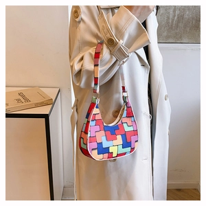 Close-up of a colorful geometric felt bag styled with a beige trench coat for a retro look