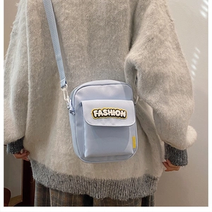 Detail of light blue nylon crossbody bag featuring fashion embroidery and adjustable strap