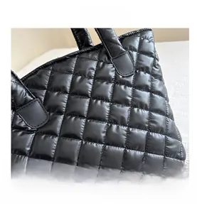 Close-up of black quilted tote bag with large diamond stitching and leather trim