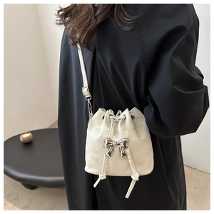 Detail view of cream pleated bucket bag with metallic silver bow and drawstring closure