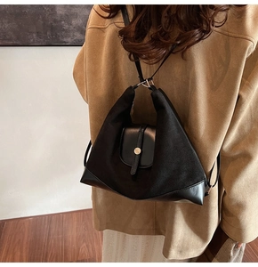 Detail of the black textured tote bag worn over a camel wool coat in a minimal setting