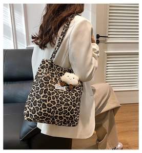 Detail view of large leopard print tote bag featuring a white plush cloud charm accessory