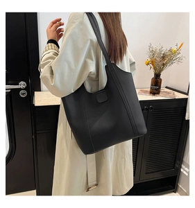 Minimalistische schwarze matte Tragetasche von einem Model im modernen Innenraum