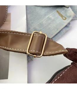 Détail de la bandoulière réglable en cuir marron avec boucle en métal doré et surpiqûres