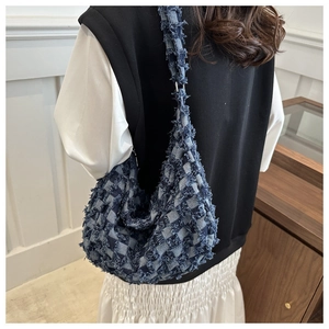 Detail of denim checkered hobo bag with fringe edges and wide shoulder strap