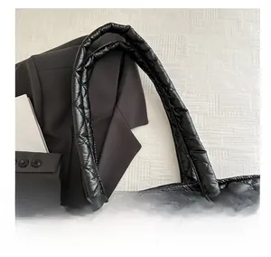 Detail show of black quilted tote bag with reinforced handles and nylon texture