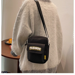 Rear view of a black canvas crossbody bag featuring a plush 3D FASHION letter patch