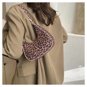 Close-up of a leopard print crescent bag styled with a khaki blazer on a shoulder