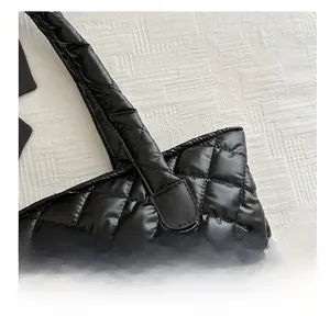 Close-up of black quilted tote bag with wide shoulder strap and puffer nylon texture