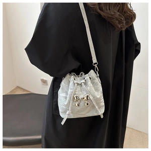 Detailed view of silver drawstring bucket bag with metallic bow and pleated texture