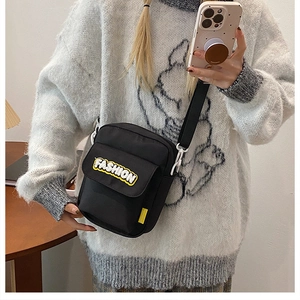 Close-up of black canvas bag featuring yellow FASHION embroidery and adjustable strap