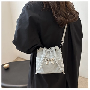 Detailed view of the gray bucket bag featuring a large silver bow and pleated texture