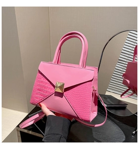 Detail of pink faux crocodile leather bag with golden square rivet and envelope flap