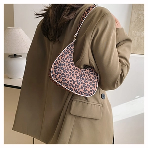 Detail of leopard print crescent bag with white piping shown as a stylish underarm bag