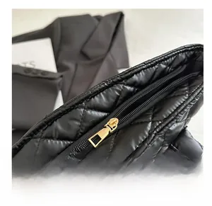 Close-up of smooth gold metal zipper detail on a black quilted leather tote bag