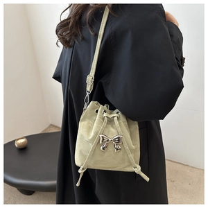 Close-up of light green drawstring bucket bag featuring a silver metal bow decoration