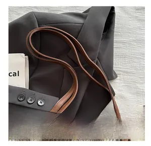 Nahaufnahme der braun-karierten Tweed-Tasche mit Ledergriffen und Metalldetails