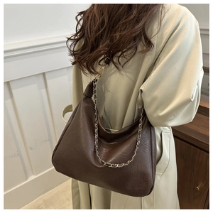Sac hobo en similicuir marron foncé avec chaîne dorée porté par un mannequin