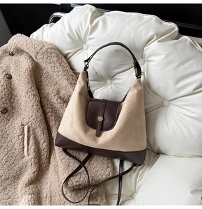 Detailed view of beige suede and brown leather tote bag on white quilted sofa