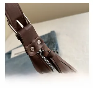 Detail of smooth metal zipper and silver rivets on dark brown leather shoulder bag