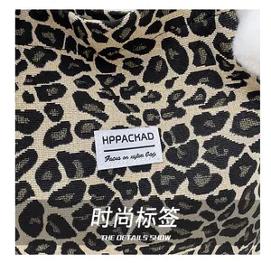 Close-up of leopard print nylon tote bag with brand woven label and gold thread texture