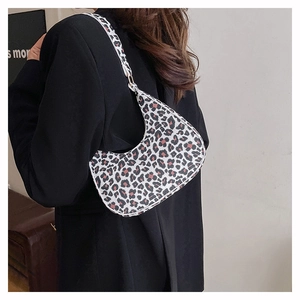 Close-up of stylish leopard print crescent bag on shoulder with minimalist black blazer