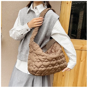 Detailed view of brown quilted tote bag with heart-shaped stitching pattern on shoulder strap