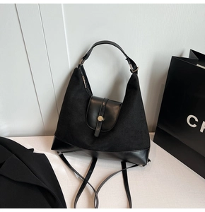 Close-up of black suede and PU leather patchwork bag with golden metal snap fastener