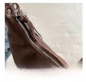 Detailed macro view of the smooth zipper closure and texture on brown leather tote bag